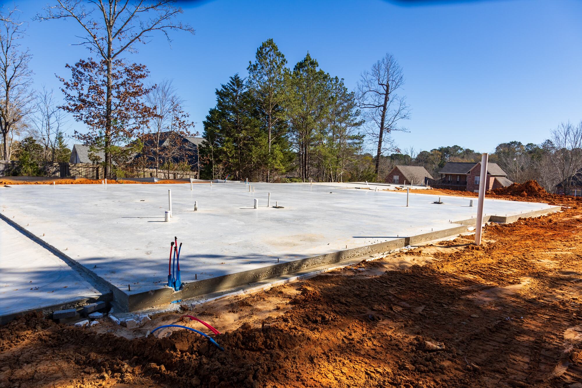 New concrete foundation slab with plumbing stub-outs on a building site