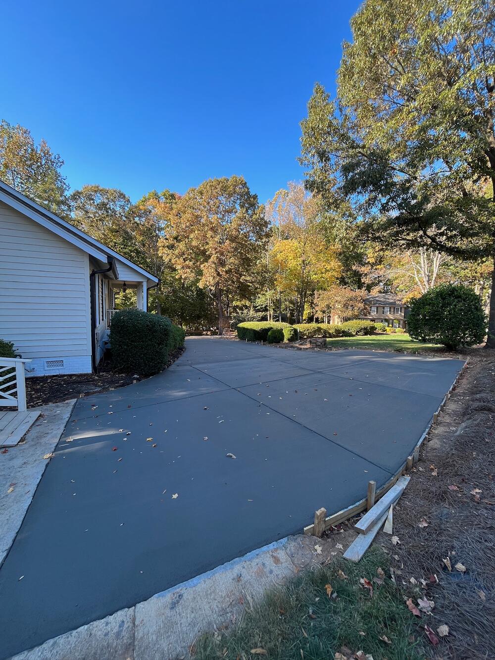 New concrete driveway with a wide parking area beside a house