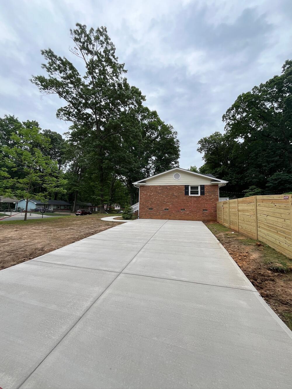 Long straight concrete driveway leading to a brick garage