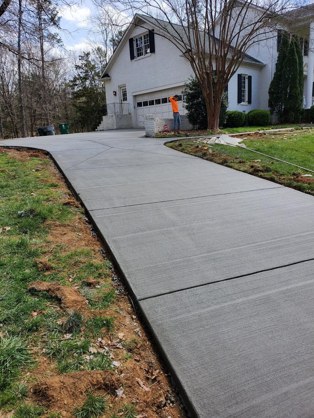 Smooth concrete driveway curving along a lawn toward a garage