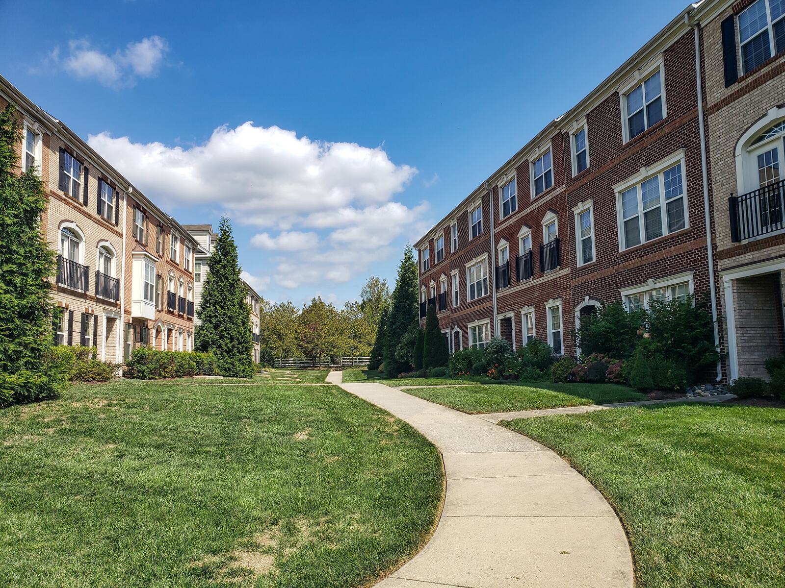 Wide concrete path curving past an apartment building